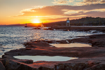 Sailboat entering the harbor at Grand Marais viewed from Artist's Point at sunset on an autumn day