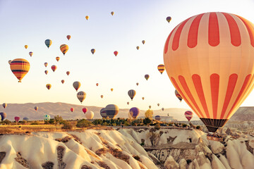 Obraz premium Cappadocia, Turkey. A sky full of colorful hot air balloons drifting peacefully at sunrise above the ancient volcanic landscape. A serene and cinematic morning scene.