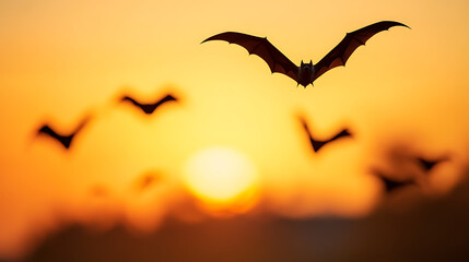 Naklejka premium Bats take flight against a sunset sky, silhouettes dancing in the warm light. The image evokes a sense of mystery and the natural beauty of dusk.