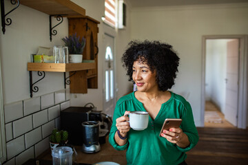 Mature woman having coffee and using a phone
