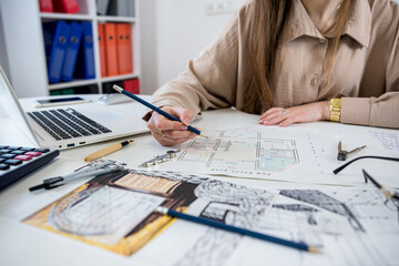 Professional female interior designer working with house sketch plan in office, workplace