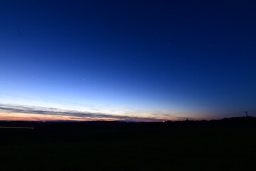 Beautiful sunset over Czech nature in Silesia during an October evening. The night sky slowly appears above the colorful horizon, blending warm sunset tones with the deep blue of approaching night.