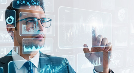Professional businessman with glasses interacting with futuristic holographic data displays showing financial charts and global analytics, planning future strategies.