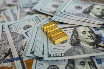 Shiny gold bullion bars on hundred dollar banknotes representing luxury, savings and financial...