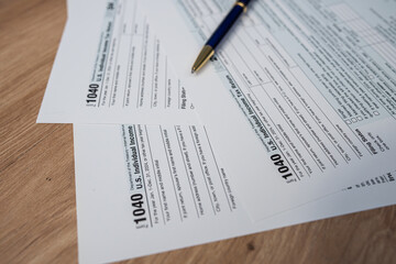 Obraz premium US Income Tax Return Form 1040 for 2024 with a pen on a wooden table.
