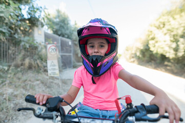 Girl wearing helmet driving quad bike on rural road