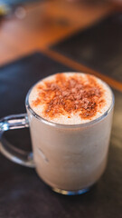 Refreshing iced coffee in a glass, topped with a dusting of chocolate powder. Condensation on the glass, perfect for summer menus and cafe promotions.