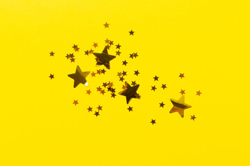 Golden star shape confetti on color background, top view