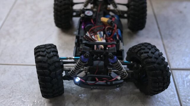 Close-up of an RC car chassis with visible electronics as the wheels turn left and right, accompanied by realistic servo motor sound
