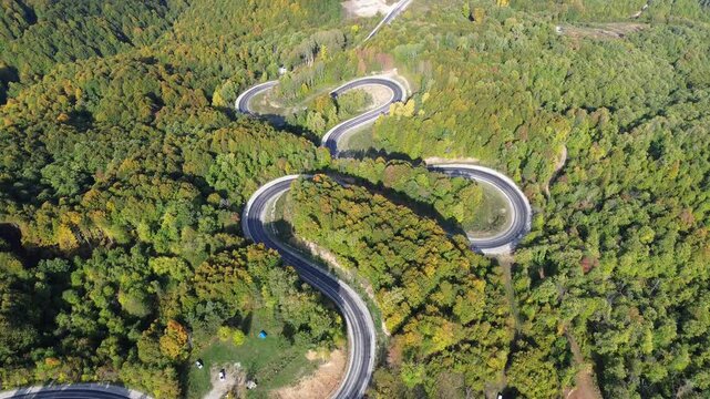 The colors of the tree leaves in the mountains in autumn and the winding, dangerous road. 