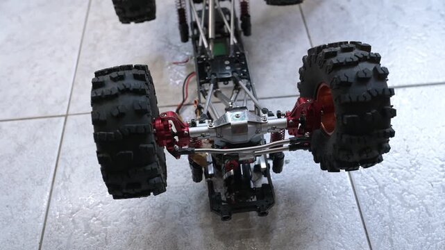 Close-up of an RC car chassis with visible electronics as the wheels turn left and right, accompanied by realistic servo motor sound