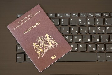 Netherlands passport lies on black laptop keyboard buttons background close up. Technologies and control in Europe concept