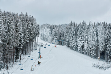 Ski slope with a chairlift through a snowy forest.