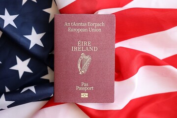 Ireland passport on big waving flag of United States of America close up. US Visa and immigration...