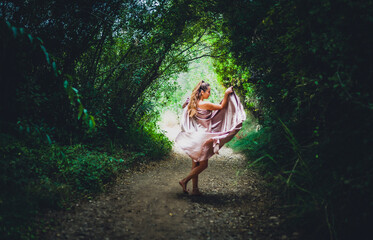 woman in flowing dress walking through forest fairy tale atmosphere