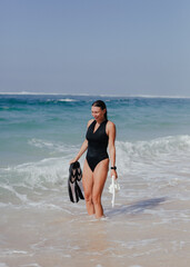 Beautiful woman surfer with snorkeling gear smiling on tropical beach