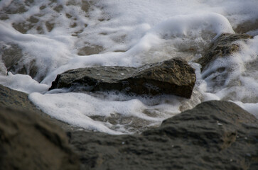 Sea Foam Swirling Around Dark Coastal Rocks