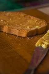 Golden Toast with Melted Butter Being Spread on a Rustic Wooden Cutting Board