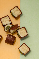 Pieces of chopped chocolate candies with nut filling on a two-color background