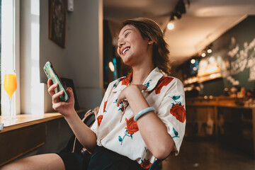 Asian woman holding stylus and talking on phone, raising finger, symbolizing creative idea,...