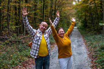 Happy Active mature couple walking through autumn forest trail together showing love and unity, happiness forest trail, golden years, outdoor activity, scenic route
