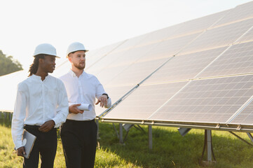 Engineers inspecting solar panels at renewable energy farm