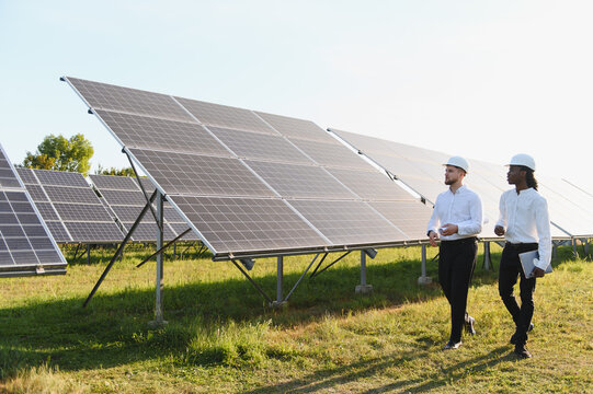 Engineers inspecting solar panels at green energy farm - Powered by Adobe