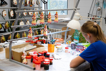 Woman painting Decorative Christmas tree decoration nutcracker in a craft studio with colorful...