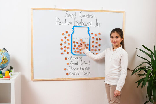 A teacher&rsquo;s classroom uses a positive behavior management chart filled with stickers to reward students&rsquo; achievements, promoting motivation, engagement, and self-discipline in education.