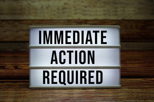 Lightbox with text "Immediate Action Required" on wooden background