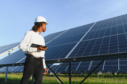 African american engineer inspecting solar panels on farm - Powered by Adobe