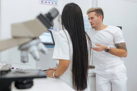 Two research assistants, female and male prepare samples for analysis in a clinical laboratory. Medical lab scientist concept.