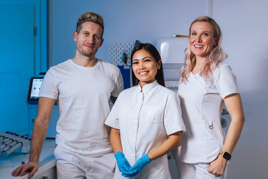 Three medical staff in bright clinic uniforms and gloves highlight teamwork and professionalism.