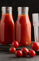 Full glass bottle with tomato juice on dark background