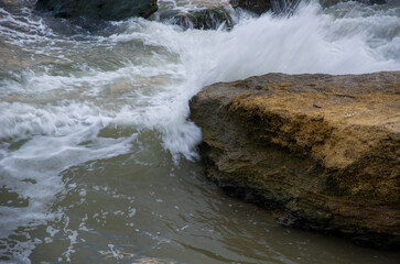 Powerful Ocean Wave Crashing Against Coastal Rock Formation with White Foamy Spray