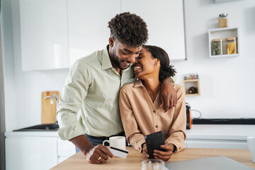 Black couple shopping online using smart phone and credit card