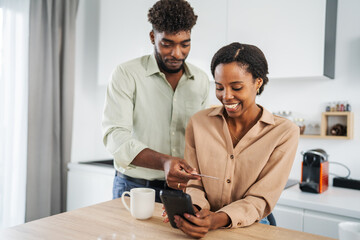 Fototapeta premium Black couple shopping online using smart phone and credit card
