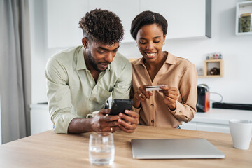Black couple shopping online using smart phone and credit card