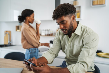 Fototapeta premium African american man using smart phone in kitchen