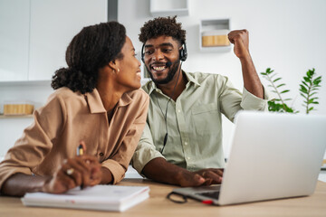 Happy black couple celebrating professional success working from home