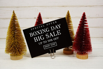 Festive display with small decorative Christmas trees with "Special Offer Boxing Day Big Sale up to 70% off, Promotion Holiday Sale Event