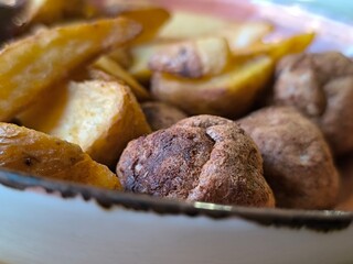 fried potato slices in a clay plate with meatballs