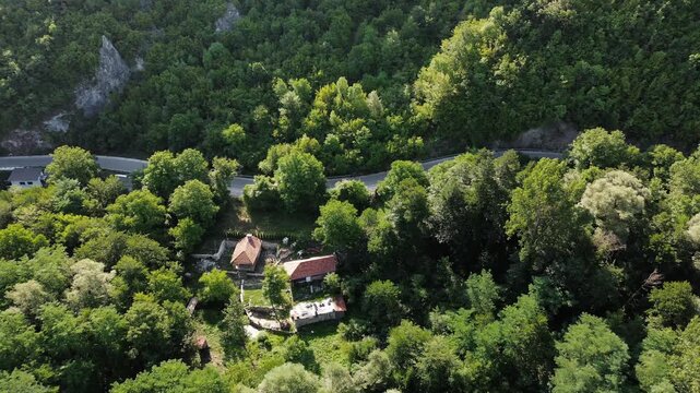 Aerial drone view of a traditional house surrounded by dense forest and mountain road on Stara Planina in Serbia. Peaceful summer landscape. Horizontal 4k footage