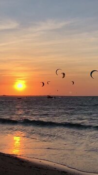 Sunset over Barra Grande Beach, Piau&iacute;, Brazil. Silhouettes of kitesurfers and boats on calm ocean waters with vibrant orange sky.