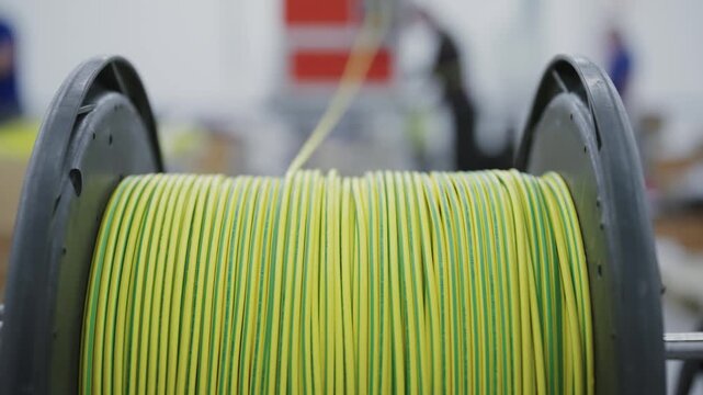 Detail of plastic spool with yellow cable wound around in industrial manufacturing production plant environment