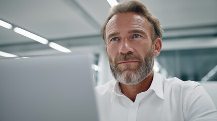 Busy caucasian male bank manager focused on laptop while analyzing financial report in modern office environment