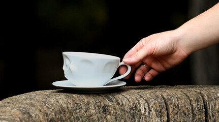 close up hand taking a white cup of coffee from a wooden table