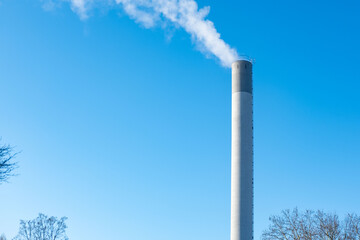 tall industrial chimney releasing smoke into clear blue sky, industrial activity and potential environmental concerns, Emissions from an industrial facility