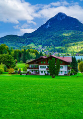Vertical shot: Alpine village houses and lush rolling hills by Lake Wolfgangsee, Austria