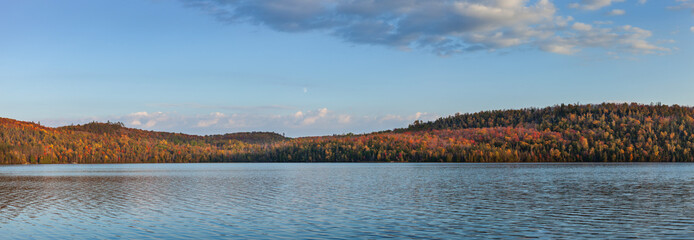 Panorama of a northern Minnesota lake under hills and trees in fall color at sunset